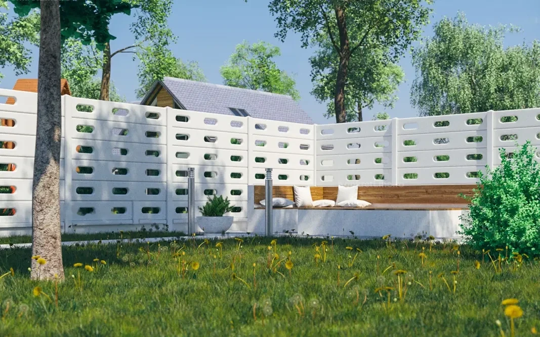 Białe ażurowe ogrodzenie betonowe z podłużnymi otworami wokół ogrodu